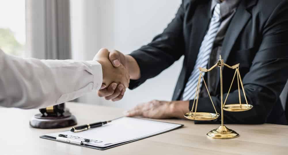 Lawyer and client shake hands during consultation