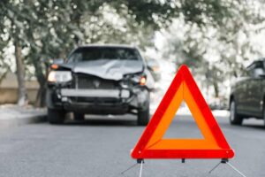 Red emergency stop triangle sign on road in car accident scene.