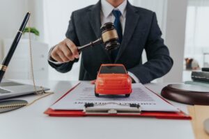 Car accident attorney with gavel in hand and model of car on the table