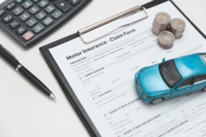 Motor or car insurance claim form with coin stack, calculator and car model.