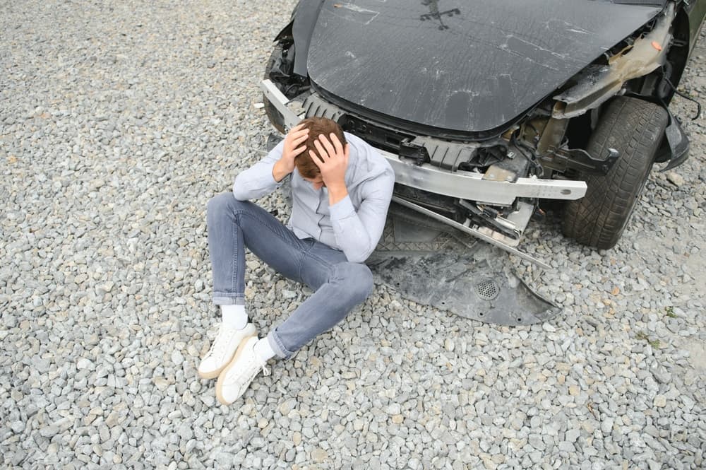 Man after car accident. Man regrets damage caused during car wreck.
